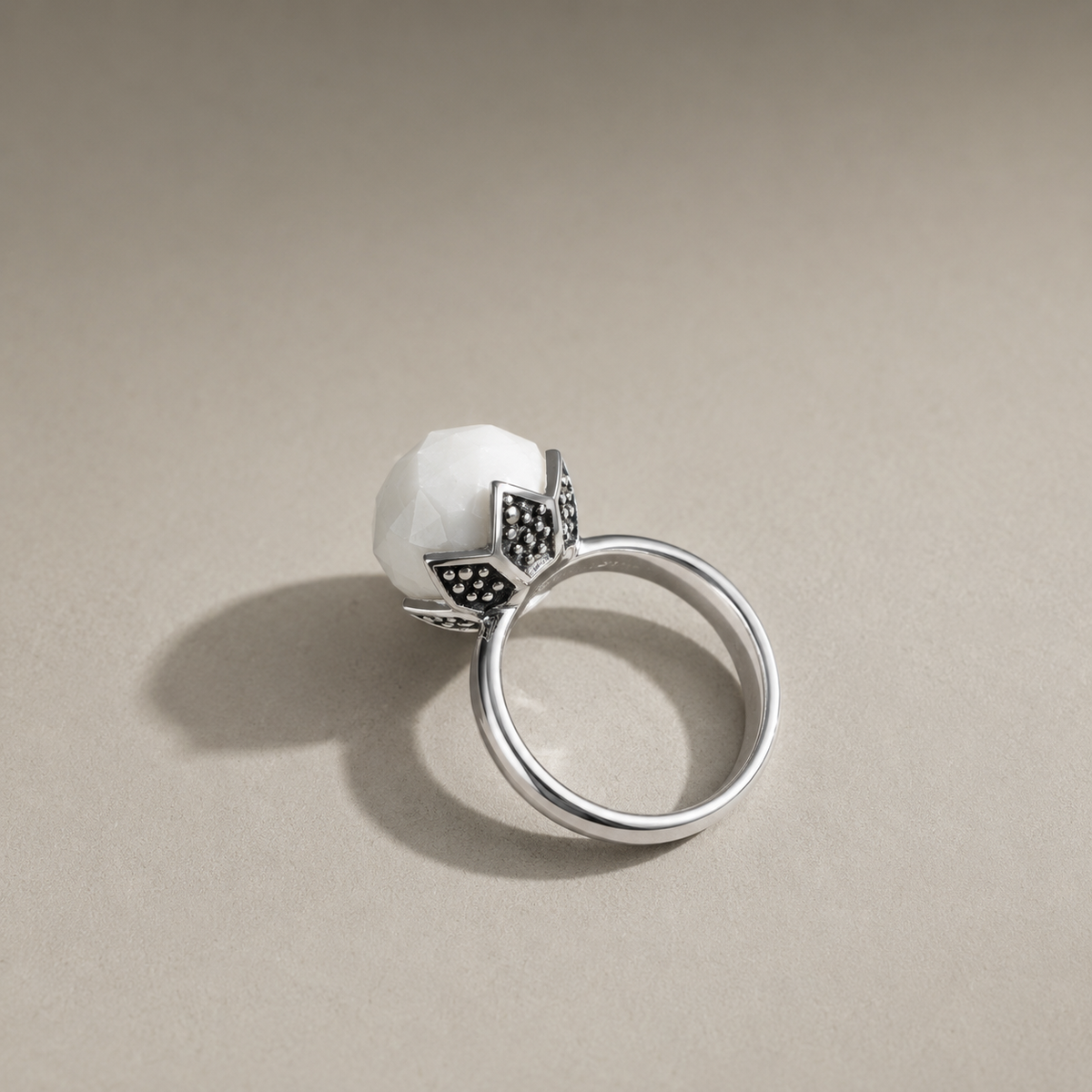 Unaze Luna U3178 prej celiku inox me agat te bardhe, montim me motive petalesh dhe detaje te erreta, pamje anesore mbi siperfaqe bezhe | Penelope Jewellery