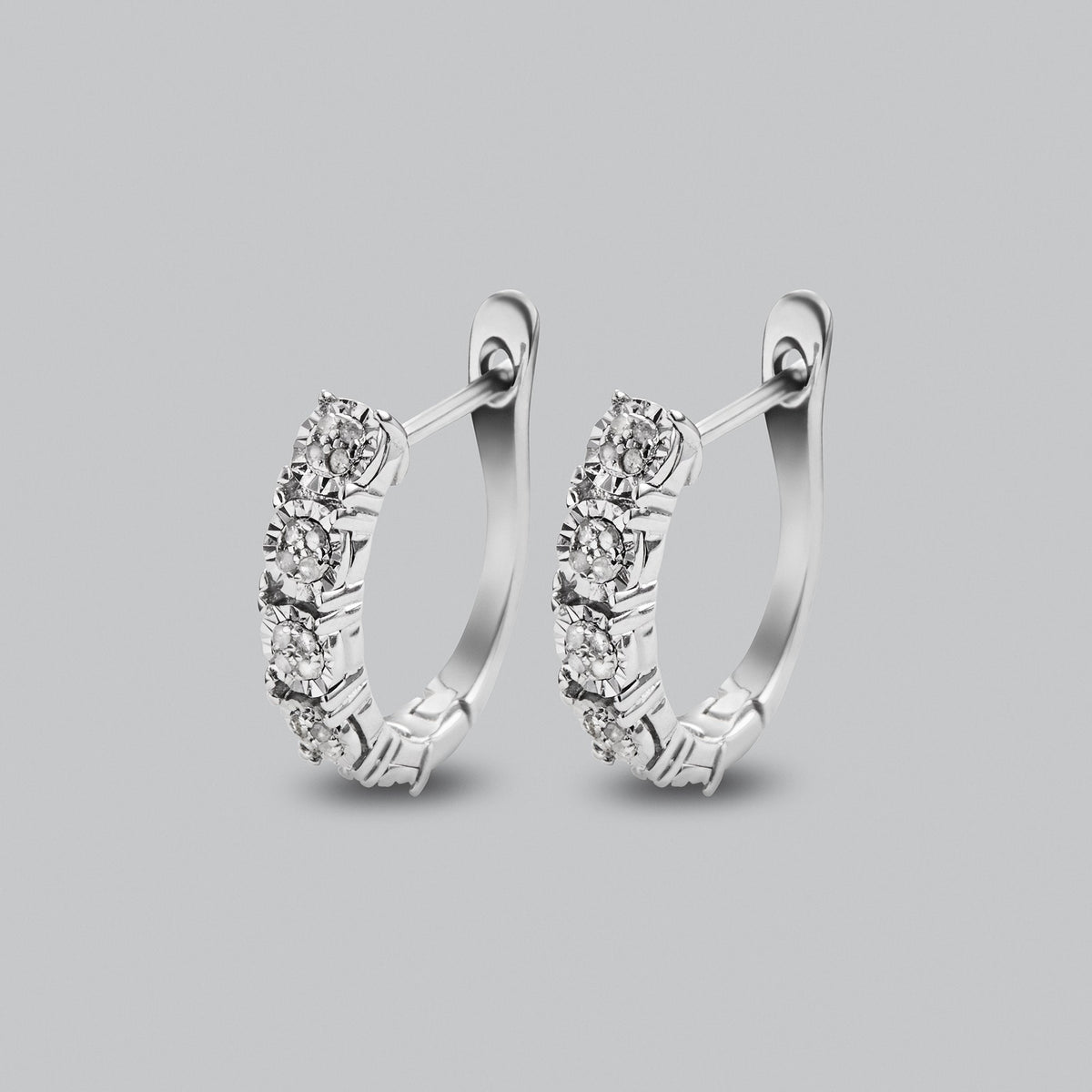 Silver hoop earrings with round clear gemstones set in a row on a light grey background